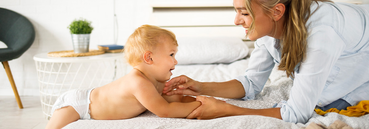 Woman playing with baby wearing diaper