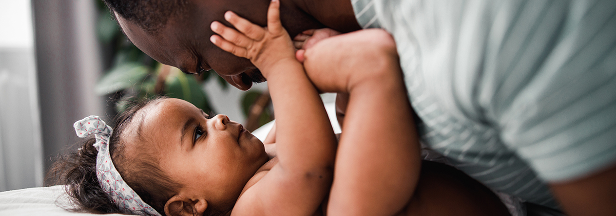 Black baby girl playing with her father's face