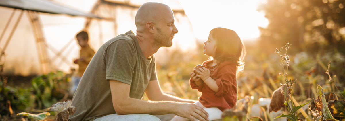 Dad fooling around with his toddler daughter in tall grass