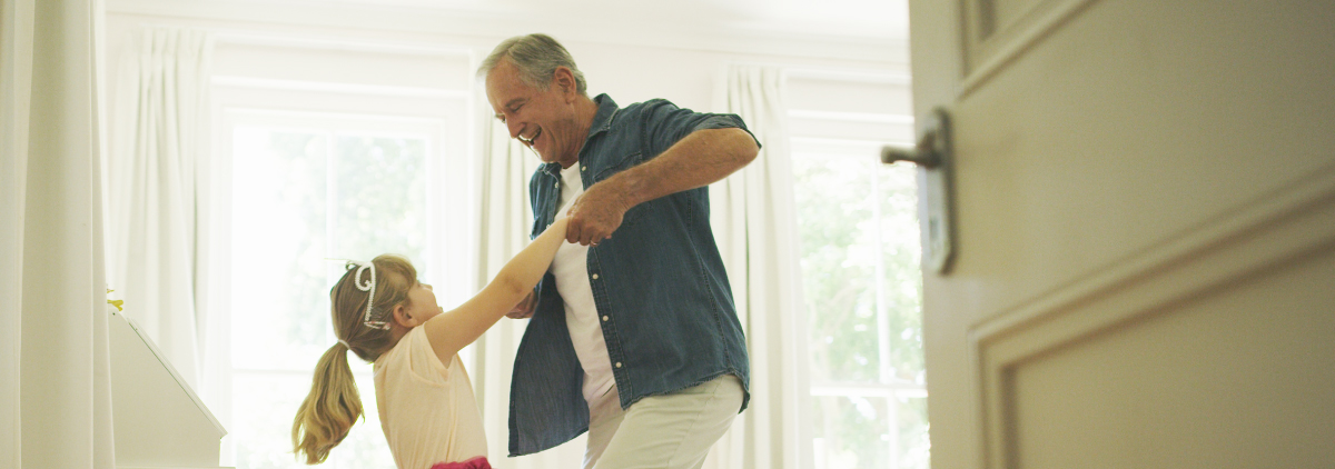 Senior man playing Ring Around the Rosie with little girl