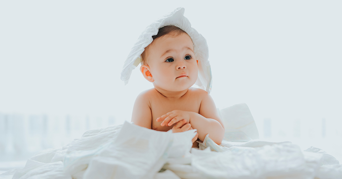 baby pops out a pile of diapers