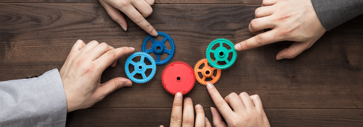 Hands sliding cogs of different colors on a wooden surface