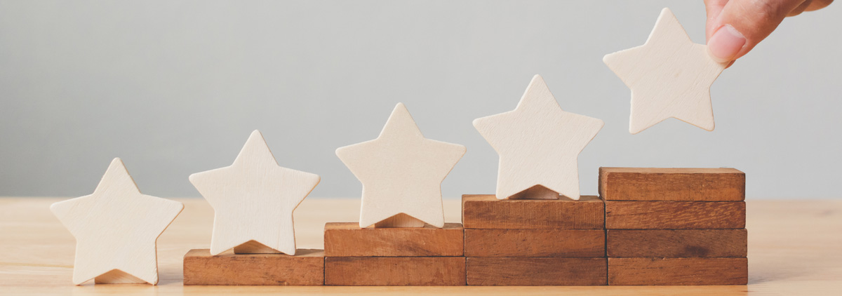 Hand putting white stars on wooden blocks gradually increasing in hight. 