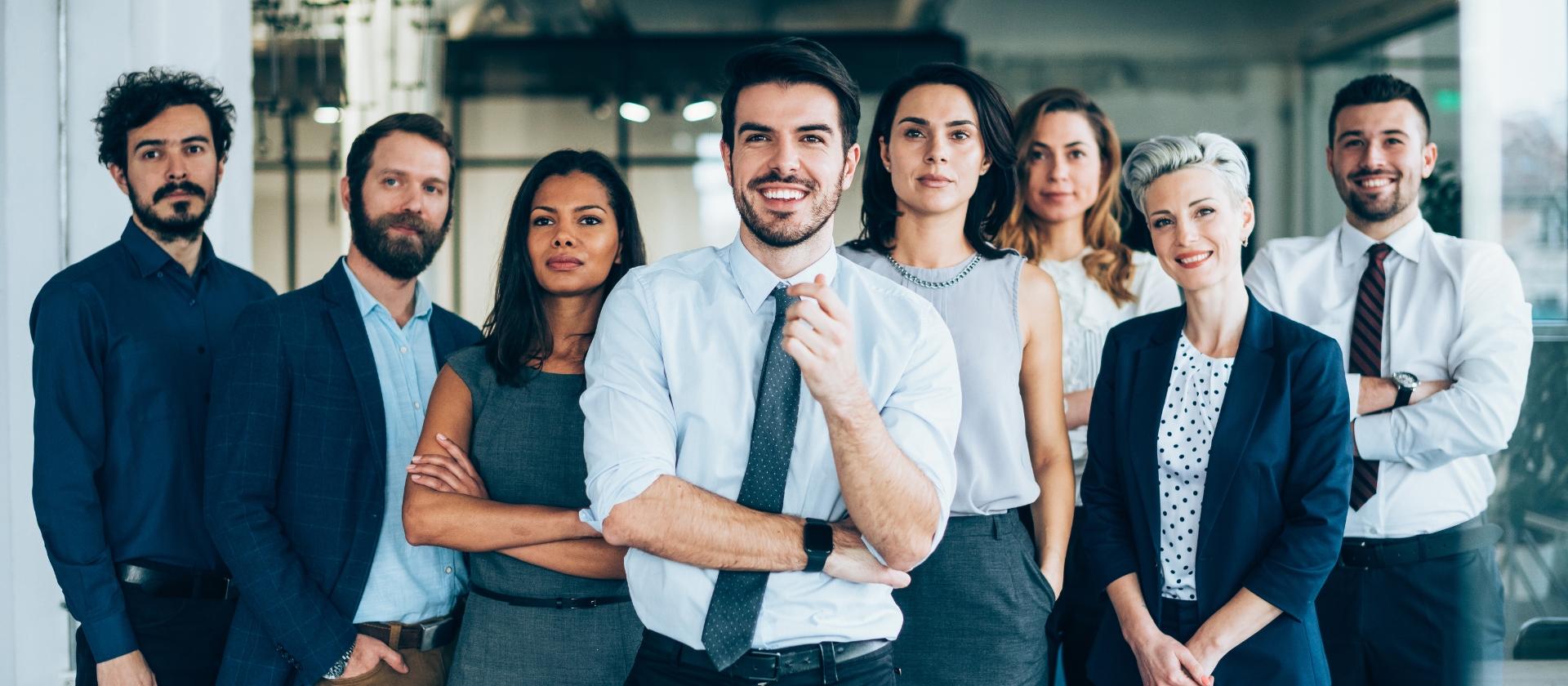 A group of diverse people, in business clothes, smiling towards you.