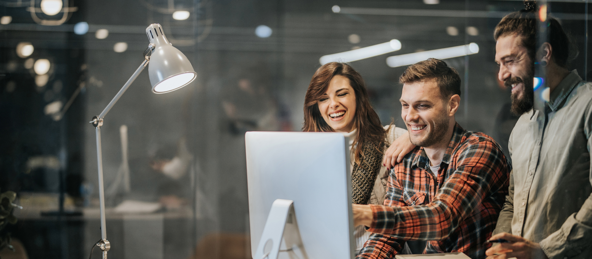 Team made of two man and a woman in front of a computer