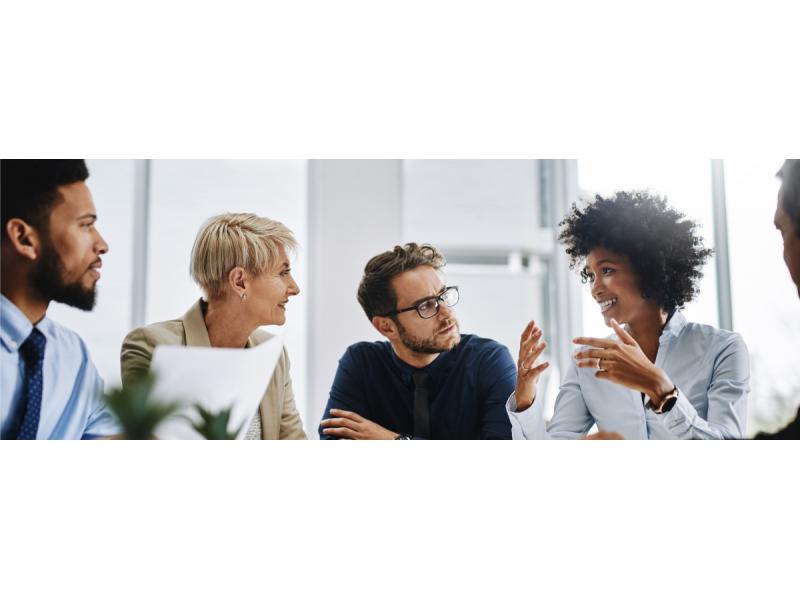 Multicultural group of colleagues having a meeting in a bright, white office.