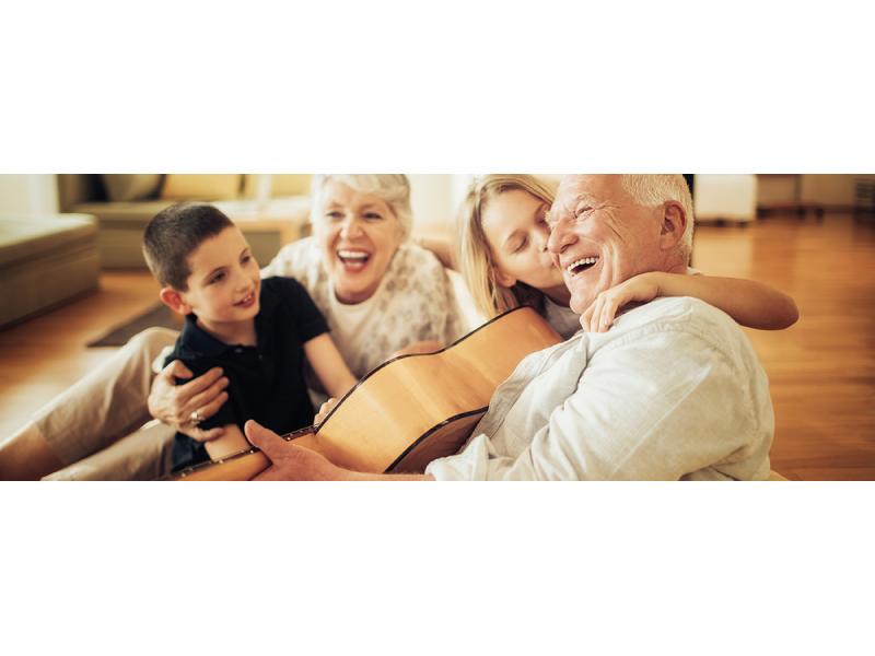 Grandparents palying guitar and laughing with younger grand son and older grand daughter.