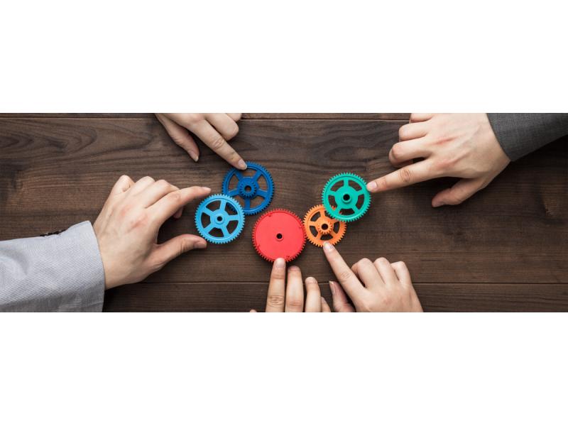 Hands sliding cogs of different colors on a wooden surface